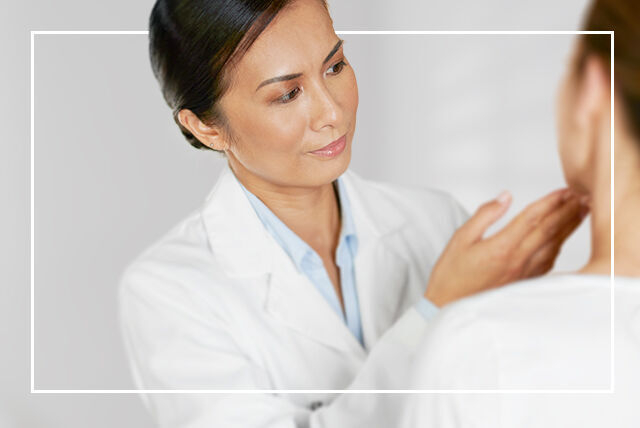En kvinnelig lege sjekker en pasients lymfeknuter i nakken med hånden